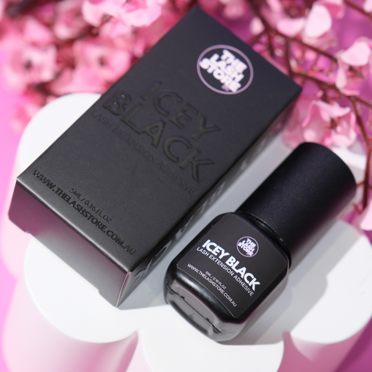 Black nail polish bottle and packaging with 'Icey Black' branding on a pink floral background.