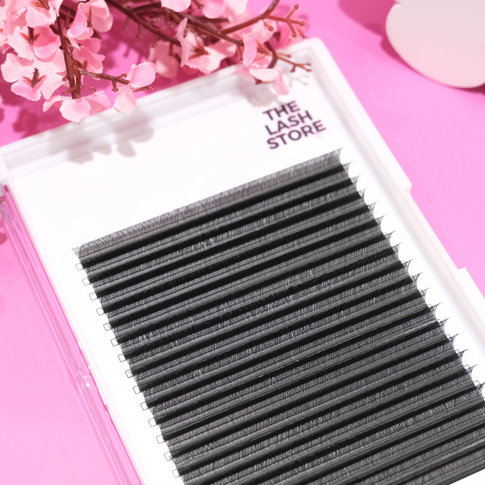 Eyelash extensions on a tray with 'The Lash Store' branding against a pink background with flowers.